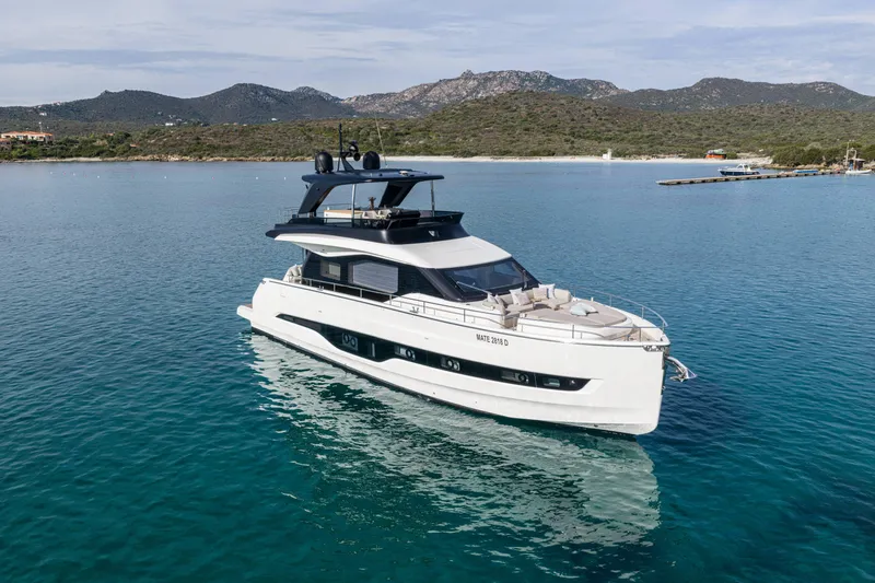 The Image of 2026 Cranchi Sessantadue 62 yacht on serene blue waters with scenic mountain backdrop. - 0