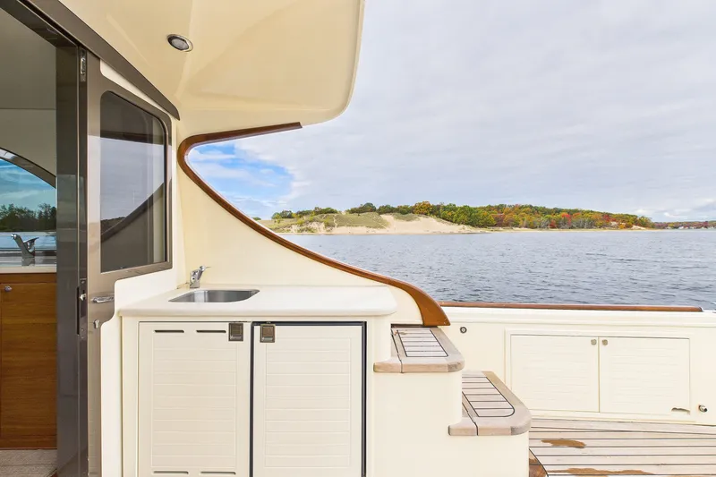 Slide: The Image of 2018 Palm Beach Motor Yachts PB50 deck with sink, overlooking serene waters and lush shoreline. - 15