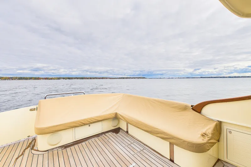 Slide: The Image of 2018 Palm Beach Motor Yachts PB50 deck with beige seating, overlooking calm waters. - 14
