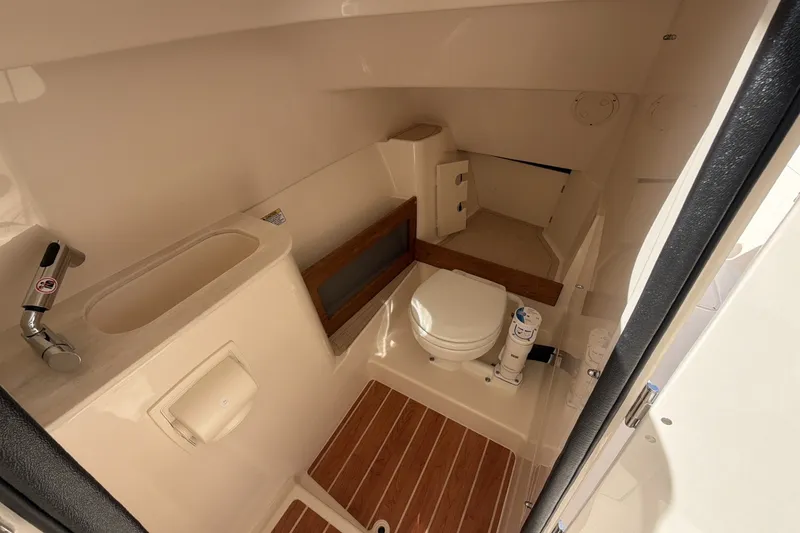 Slide: The Image of The image shows the bathroom of a Grady-White Freedom 285. It features a toilet, sink, and wood flooring. - 13