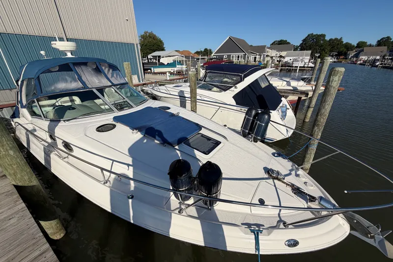 Slide: The Image of 2003 Sea Ray Sundancer 320 docked at marina, featuring sleek design and blue canopy. - 2