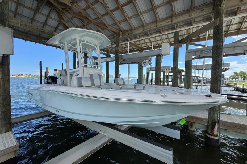 The Image of 2025 Robalo 226 Cayman boat docked under a wooden shelter by the water. - 1