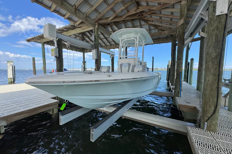 Slide: The Image of 2025 Robalo 226 Cayman boat docked under a wooden shelter by the water. - 4