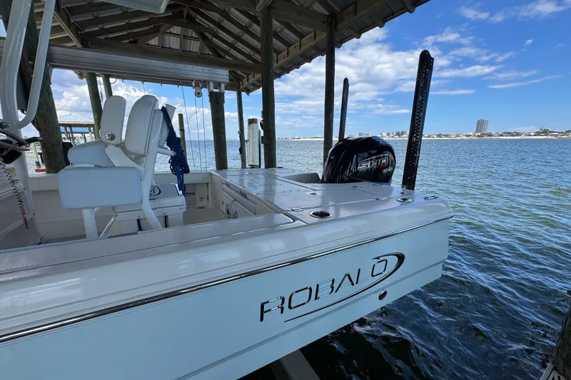 Slide: The Image of 2025 Robalo 226 Cayman boat docked under a wooden shelter by the water. - 7
