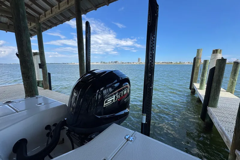 Slide: The Image of 2025 Robalo 226 Cayman boat docked, featuring a powerful outboard motor, with scenic waterfront view. - 35