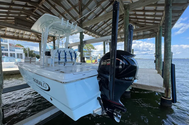 Slide: The Image of 2025 Robalo 226 Cayman boat docked under a wooden shelter by the water. - 8