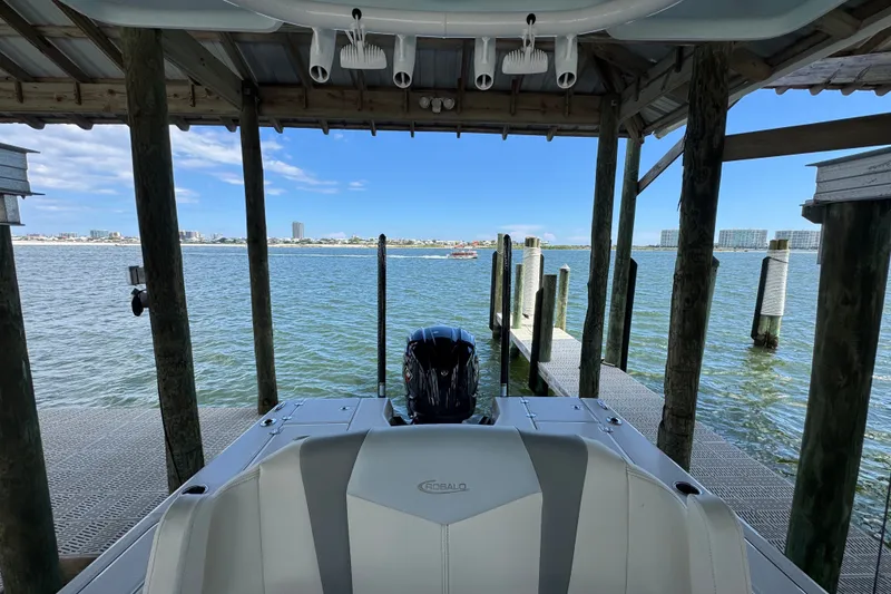 Slide: The Image of 2025 Robalo 226 Cayman boat docked under a wooden shelter with scenic waterfront view. - 23