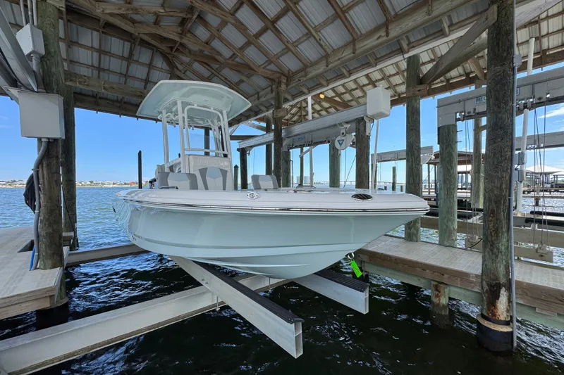Slide: The Image of 2025 Robalo 226 Cayman boat docked in a covered marina, showcasing sleek design. - 2