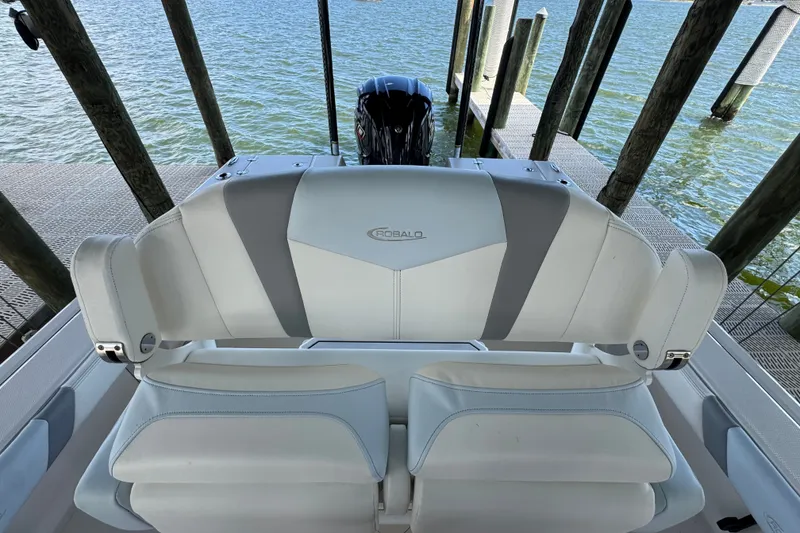 Slide: The Image of 2025 Robalo 226 Cayman boat seating with water and dock background. - 22