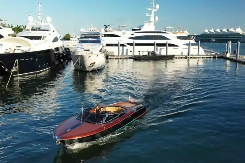 Slide: The Image of 2009 Riva 33' Aquariva boat cruising near luxury yachts in a marina. - 9