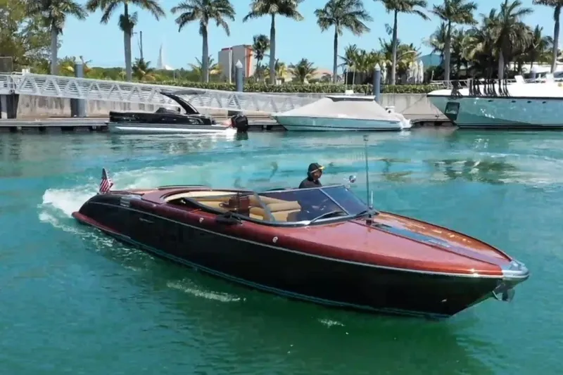 The Image of 2009 Riva 33' Aquariva luxury boat cruising in a tropical marina setting. - 0