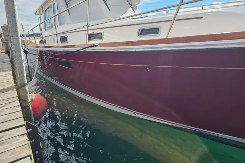Slide: The Image of 2013 Sabre 48 Salon Express yacht docked, showcasing sleek maroon hull and elegant design. - 5