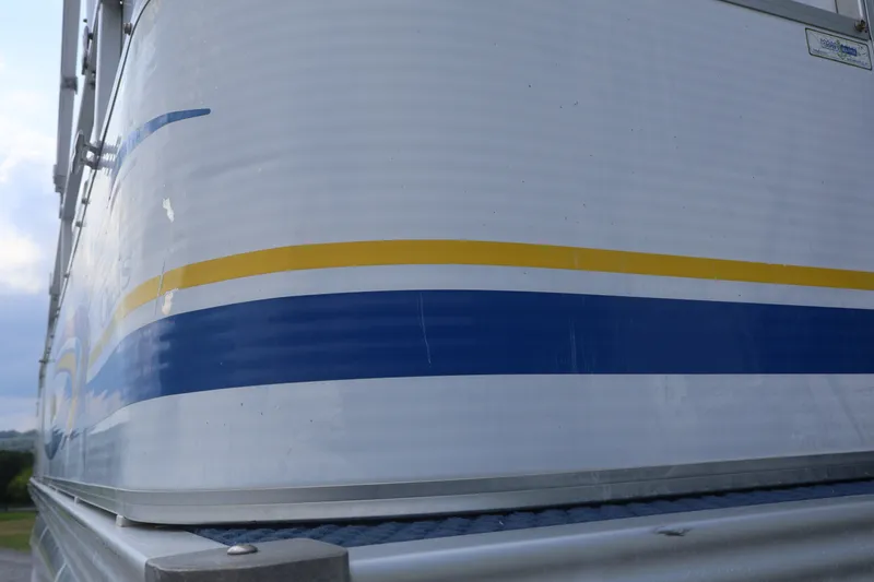 Slide: The Image of Close-up of 2007 Manitou 22 Oasis boat with blue and yellow stripes. - 24