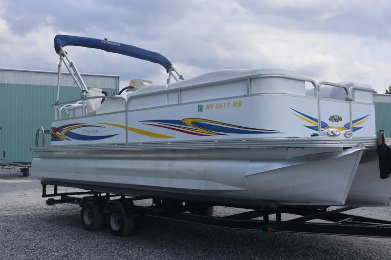 The Image of 2007 Manitou 22 Oasis pontoon boat on trailer, featuring colorful graphics and canopy. - 2