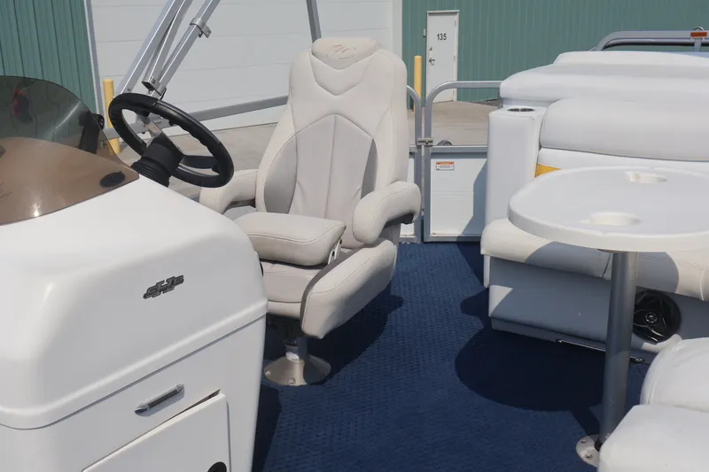 Slide: The Image of 2007 Manitou 22 Oasis boat interior with captain's chair and table on blue carpet. - 66