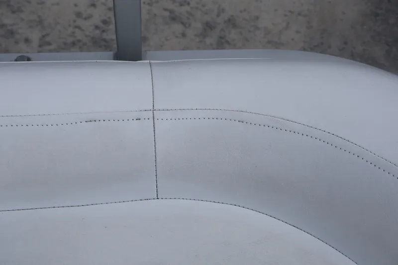 Slide: The Image of White leather seating on a 2007 Manitou 22 Oasis boat, showcasing stitching details. - 32