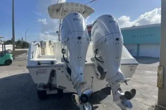 Slide: The Image of 2024 Cobia 262 Center Console boat with dual outboard engines, docked outdoors. - 6