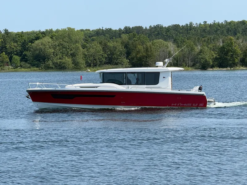 Slide: The Image of Nimbus Commuter 11, 2024, cruising on a calm lake with a wooded shoreline in the background. - 3