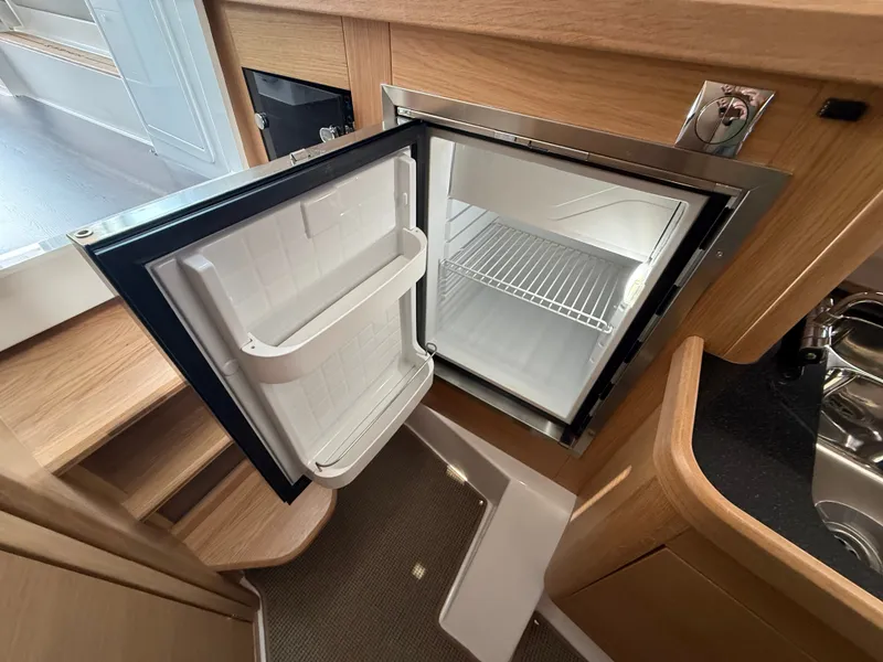 Slide: The Image of Open fridge in the galley of a 2024 Nimbus Commuter 11, featuring wood paneling. - 15