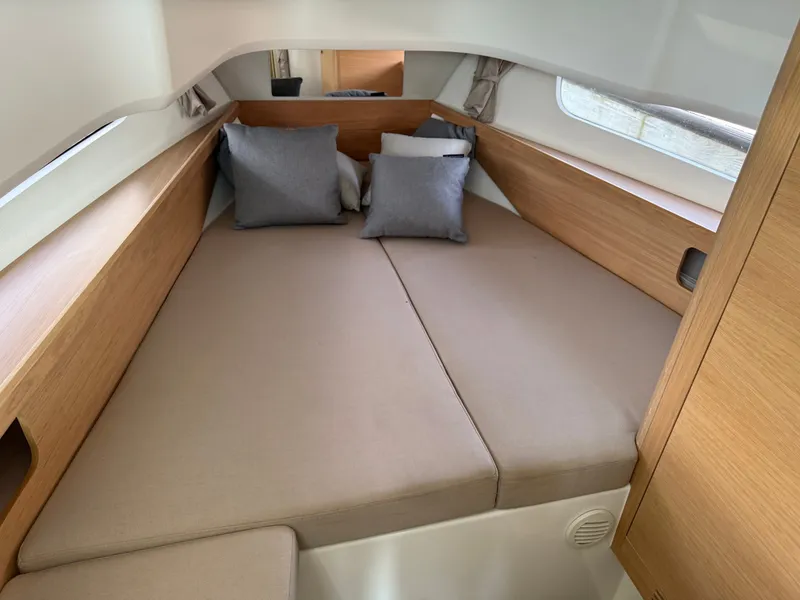 Slide: The Image of Interior of the 2024 Nimbus Commuter 11 with a cozy bed and wooden accents. - 13