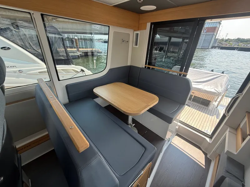 Slide: The Image of Interior of Nimbus Commuter 11 with blue seating and wooden table, overlooking the water. - 7