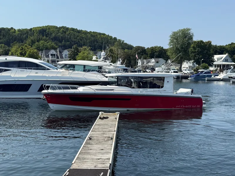 Slide: The Image of A red 2024 Nimbus Commuter 11 boat docked at a marina with other yachts nearby. - 1