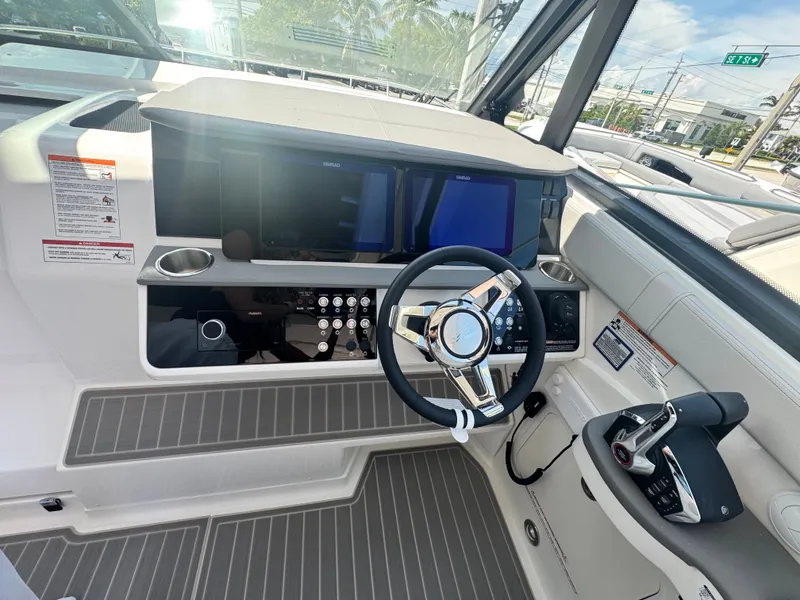 Slide: The Image of The cockpit of the 2027 Sea Ray Sundancer 320 Outboard features a modern helm with dual screens and a sleek steering wheel. - 10