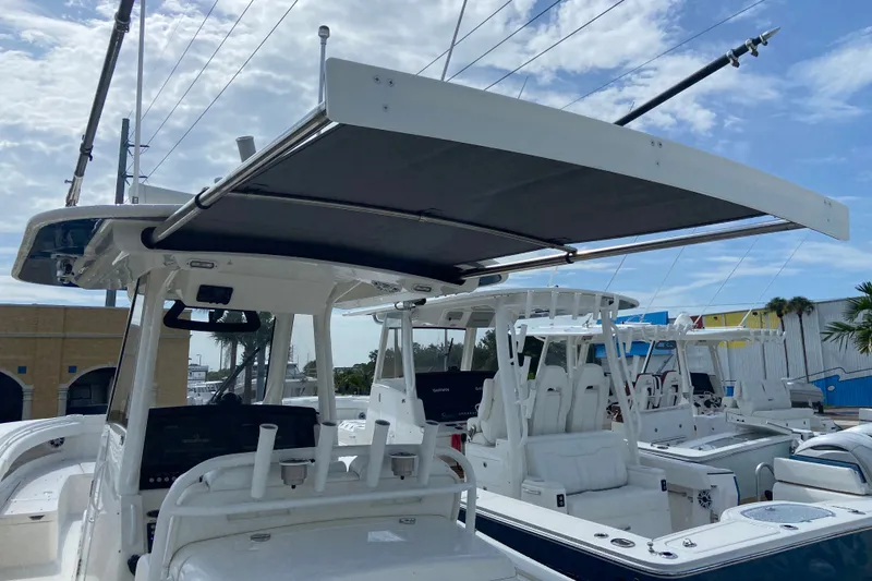 Slide: The Image of 2022 Regulator 34 boat with T-top canopy, docked under a partly cloudy sky. - 37