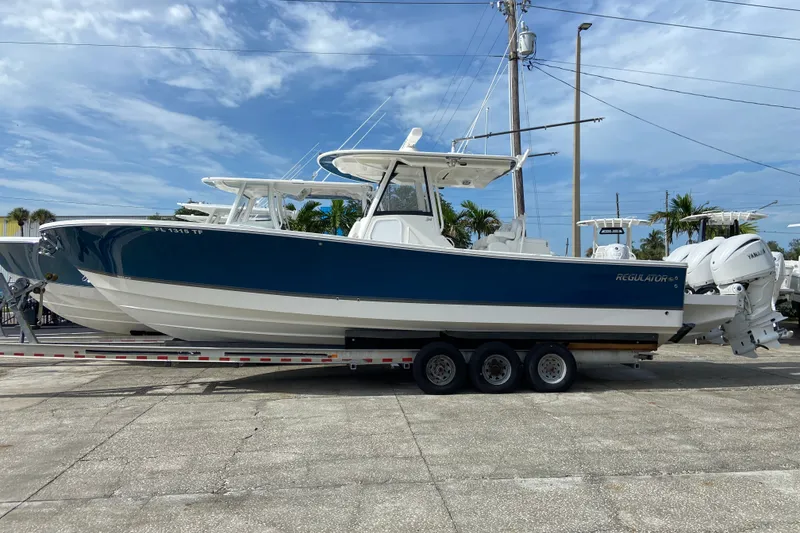 Slide: The Image of 2022 Regulator 34 boat on trailer, blue and white design, parked outdoors under clear sky. - 13