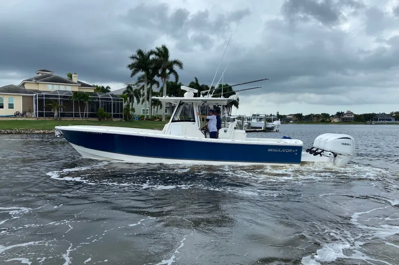Slide: The Image of 2022 Regulator 34 boat cruising on a cloudy day near waterfront homes. - 7
