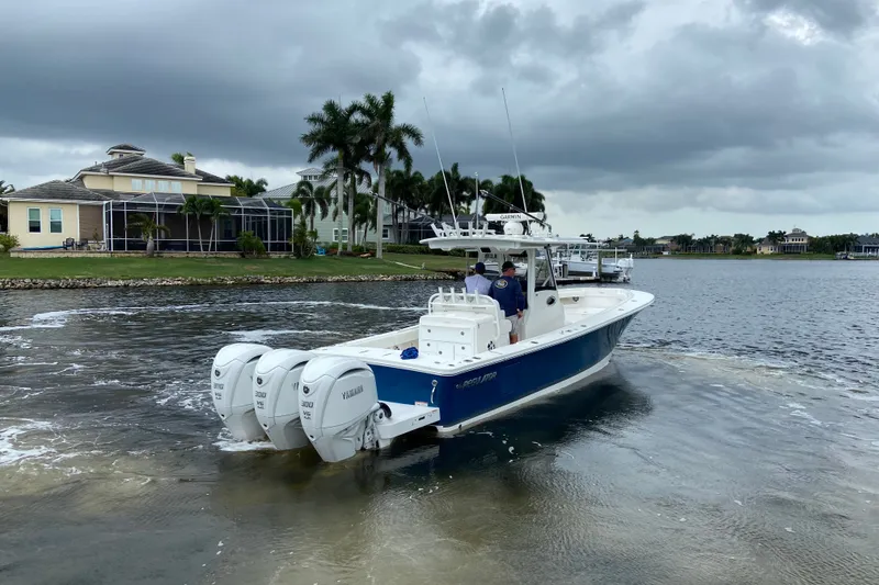 Slide: The Image of 2022 Regulator 34 boat with triple Yamaha engines on a cloudy day near waterfront homes. - 4