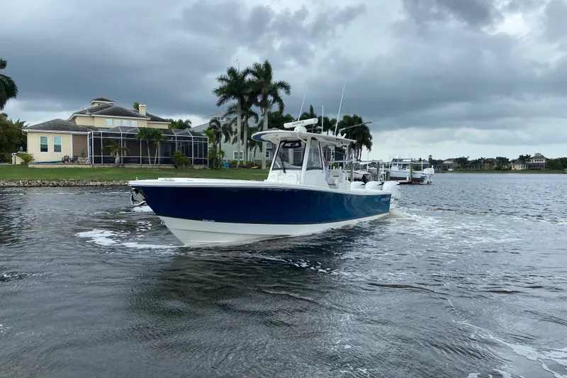 Slide: The Image of 2022 Regulator 34 boat cruising on a scenic waterway with cloudy skies. - 8