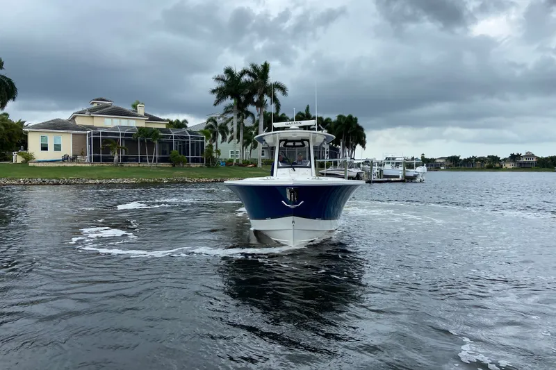 Slide: The Image of 2022 Regulator 34 boat cruising near waterfront homes under cloudy skies. - 9