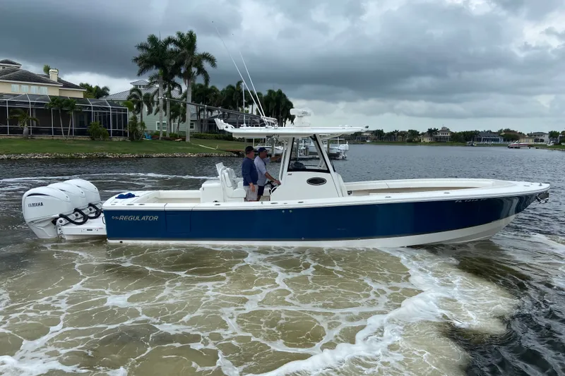 Slide: The Image of 2022 Regulator 34 boat with Yamaha engines cruising on a scenic waterway. - 2