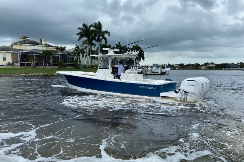 Slide: The Image of 2022 Regulator 34 boat cruising on a cloudy day near waterfront homes. - 6