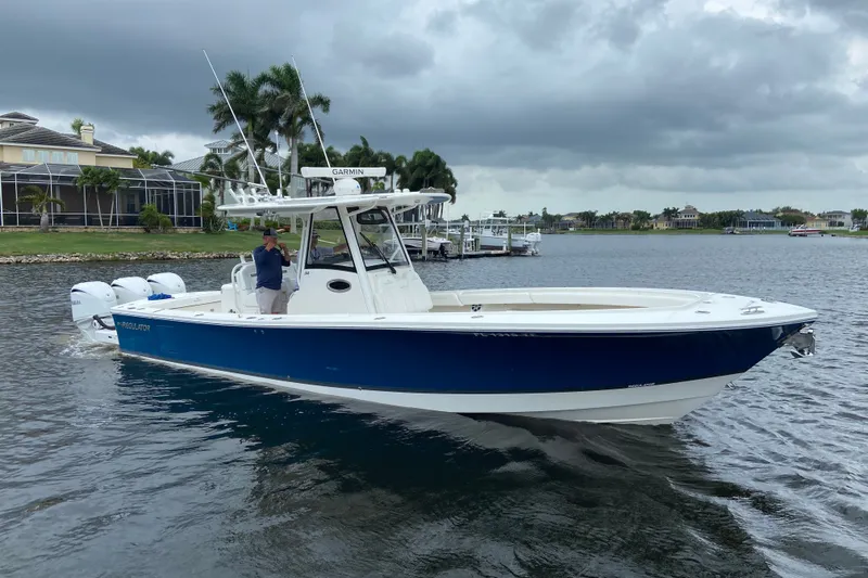 Slide: The Image of 2022 Regulator 34 boat on water, featuring blue hull and triple outboard engines. - 1