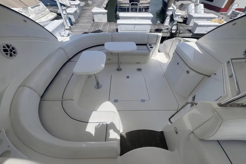 Slide: The Image of 2006 Cruisers Yachts 520 Express cockpit with white seating and tables, docked at marina. - 16