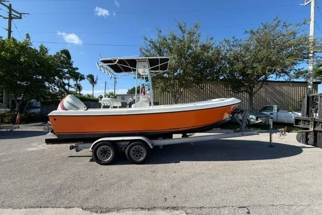 The Image of 1984 Aquasport 222 Center Console boat on trailer, orange hull, parked outdoors. - 1