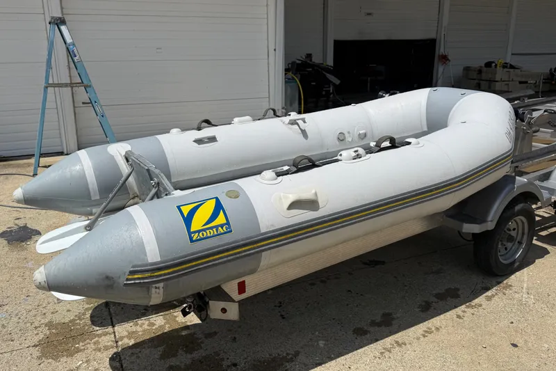 Slide: The Image of 2004 Zodiac Cadet Fastroller 310 FR Acti-V inflatable boat on trailer, parked outdoors. - 14