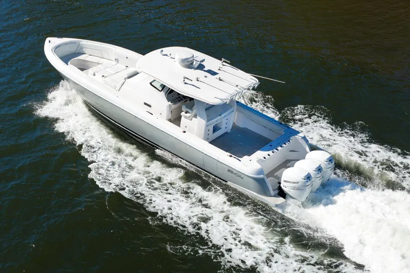 The Image of 2021 Intrepid 407 Nomad SE boat cruising on water with triple Mercury engines. - 2