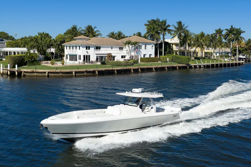 Slide: The Image of 2021 Intrepid 407 Nomad SE cruising on a sunny waterfront near luxury homes. - 1