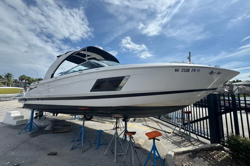 The Image of 2017 Four Winns H290 boat on stands, displayed outdoors under a partly cloudy sky. - 0