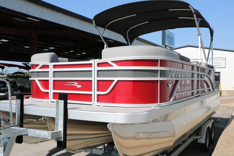 Slide: The Image of 2026 Bennington 22 SSR Tri-Toon pontoon boat with red exterior and canopy, parked on trailer. - 17