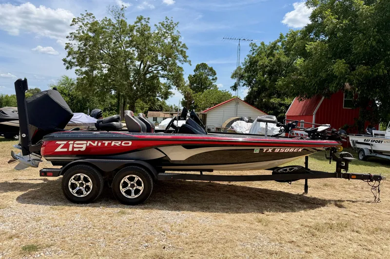 The Image of 2019 Nitro Z19 boat on trailer, parked outdoors with trees and buildings in the background. - 0