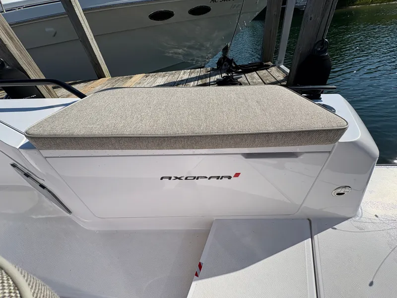 Slide: The Image of The 2024 Axopar 37 XC Cross Cabin features a cushioned bench at the stern, surrounded by a wooden dock. - 46