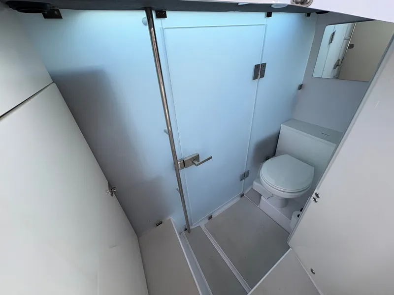 Slide: The Image of The image shows a modern boat bathroom with a toilet, mirror, and shower. - 27