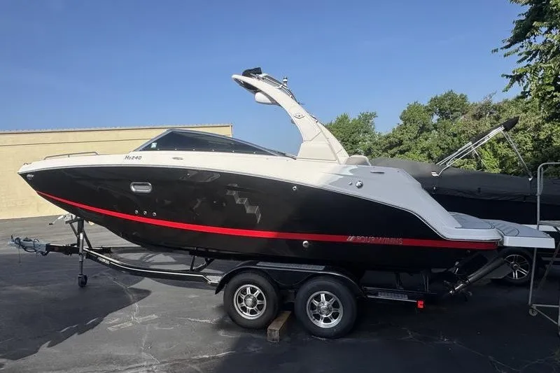 The Image of 2019 Four Winns HD240 Surf boat on trailer, black and white design with red accents. - 0