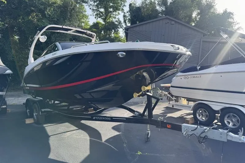 Slide: The Image of 2019 Four Winns HD240 Surf boat on trailer, parked outdoors. - 2
