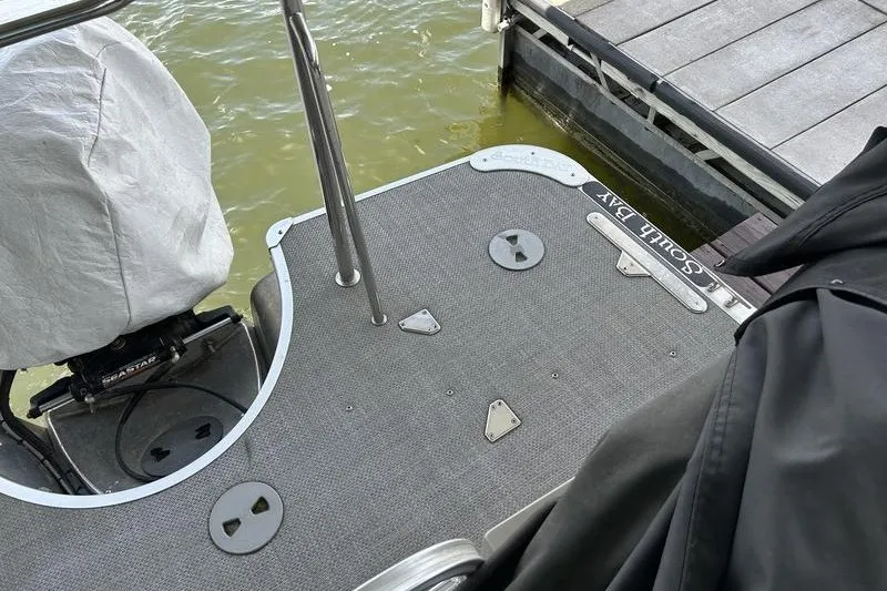 Slide: The Image of 2015 South Bay 524 SLTT boat deck near dock, featuring covered motor. - 10