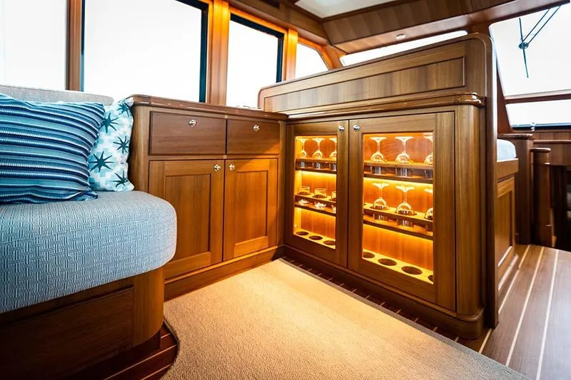 Slide: The Image of Interior of the Hunt Yachts Ocean 63 Flybridge with elegant wood cabinetry and illuminated display cases. - 42